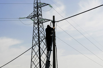 Operaio su traliccio, trave reticolare, manutenzione rete elettrica, telefono