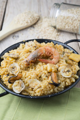 Vegetable paella with seafood on a wooden background