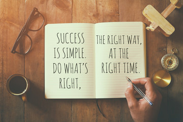 open notebook over wooden table with motivational saying