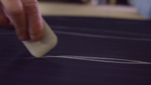  Close up on hands of a tailor working in his shop, drawing template on a piece of fabric. Shot on RED Epic.