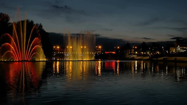 Amazing fantastic colorful fountain with bright illumination on the water pond or river with beautiful reflection at the evening or night. Beauty urban recreational concept. 4K UHD video footage.