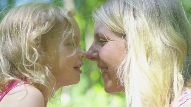  Happy affectionate mother & daughter rubbing noses together in the woods