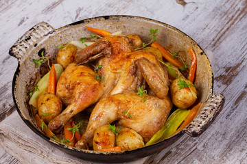 Roasted chicken with potato, carrot, leek and thyme in pan