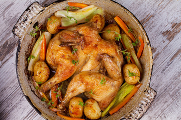 Roasted chicken with potato, carrot, leek and thyme in pan.View from above, top studio shot