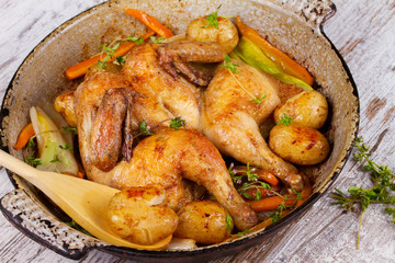 Roasted chicken with potato, carrot, leek and thyme in pan