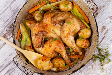 Roasted chicken with potato, carrot, leek and thyme in pan.View from above, top studio shot