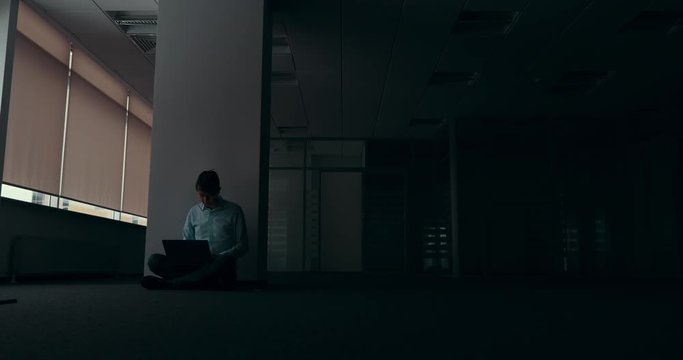 Young man working alone in empty office at night