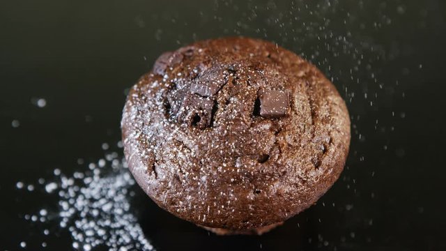 Close up of icing sugar falling onto the top of a double chocolate muffin