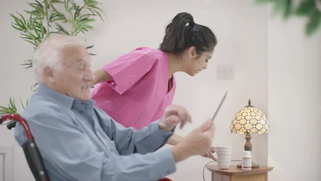  Caring home support nurse helping elderly man to use a computer
