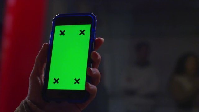  Close up of hand using a smartphone with green screen display