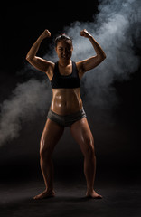 Obraz premium Young muscular woman posing on black