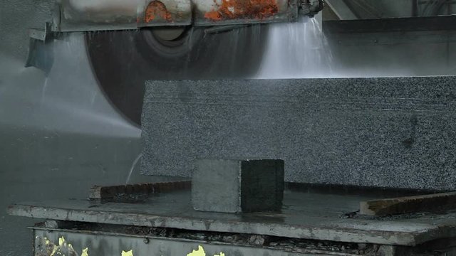 Granite processing in manufacturing. Cutting granite slab with a circular saw. Use of water for cooling