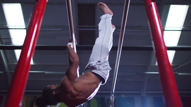  Professional male gymnast showing strength & agility on parallel bars at the 
