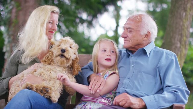  3 generations of a family spending time together in garden with pet dog