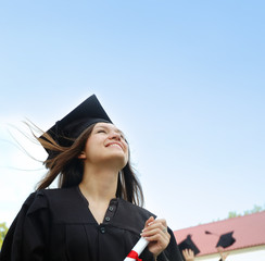 Girl in a cap and gown looking up.