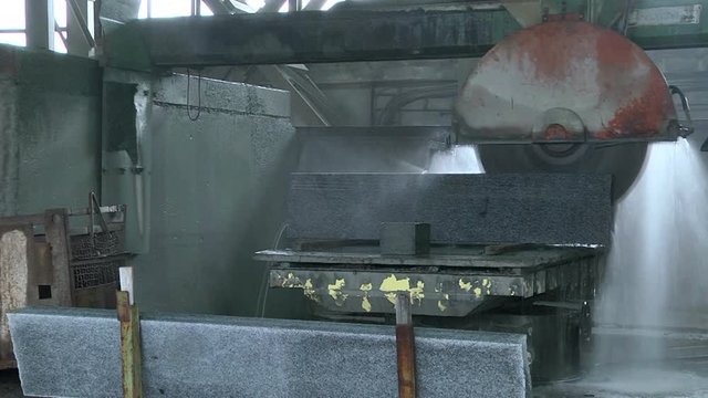 Granite processing in manufacturing. Cutting granite slab with a circular saw. Use of water for cooling