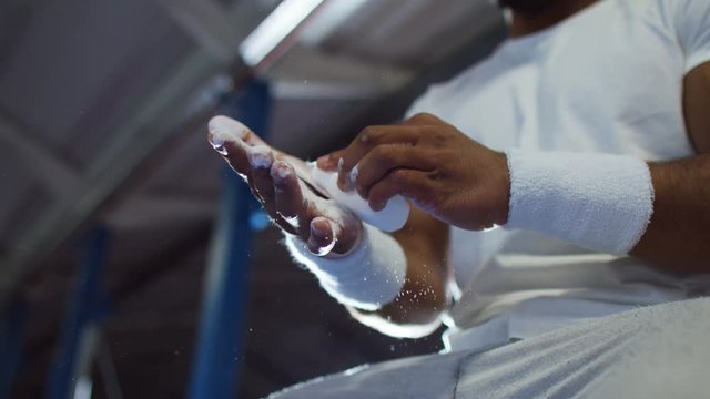  Professional male gymnast chalking his hands in preparation for training