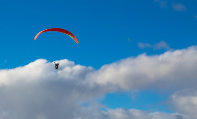 Hanglider - Paraglider high in the clouds over the ocean on a summer day