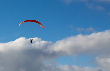 Hanglider - Paraglider high in the clouds over the ocean on a summer day