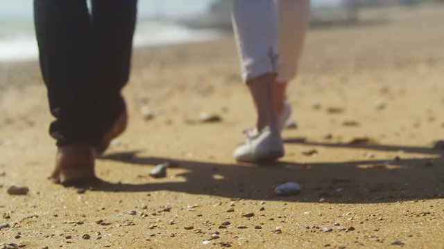 Attractive romantic couple holding hands as they walk along the beach