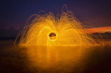 Playing steel wool nearby lighthouse sunset.