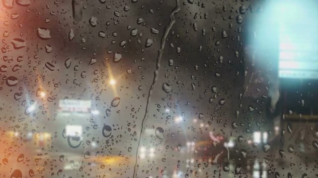 Rain on Glass - City at Night / A view through a fogged and rain splattered window (focal point) of traffic as it travels along the rain glistened streets and colorful city lights at night. 