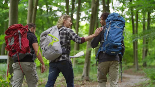  Group of male friends hiking in the woods holding map and trying to find their way. 