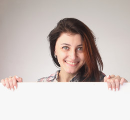 Happy beautiful Woman peeking behind a whiteboard