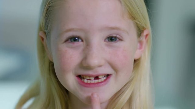  Close up portrait of little girl opening her mouth to show where she has lost one of her baby teeth. 