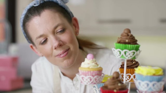  Smiling woman with bakery business putting finishing touches onto cupcakes