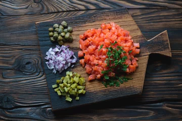 Foto auf Acrylglas Serving board with salmon tartare in a rustic wooden setting © Nickola_Che