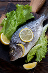 Close-up of baked dorado served with green salad and lemon