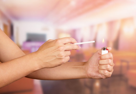 Female hand with lighter and cigarette in cafe