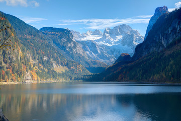 Fototapeta na wymiar Autumn scenery of Lake Gosausee with snow-capped Dachstein Mountain in the background & beautiful reflections on smooth water, in Gosau, Austria ~ A dramatic scene of unspoiled nature of Alps