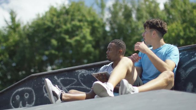  Friends at skate park, looking at computer & doing parkour jumps