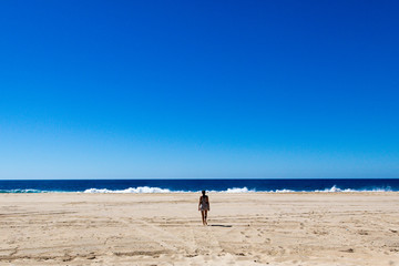 Fototapeta na wymiar Young woman walking in a empty beach in baja California, Mexico