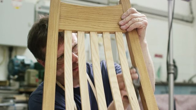  Furniture maker in his workshop, putting finishing touches to a rocking chair