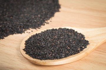 scoop of black sesame in front of a blurry pile of black sesame.