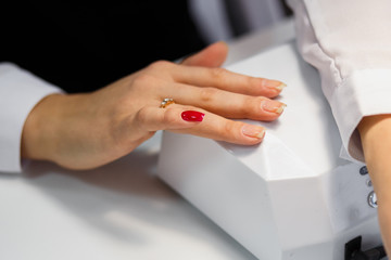 Obraz premium Manicure care procedure, Close-up photo Of Beautician Hand Painting Nails Of Woman In Salon