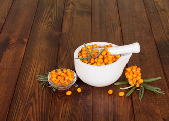 Fresh sea buckthorn berries in a mortar and pestle close up 