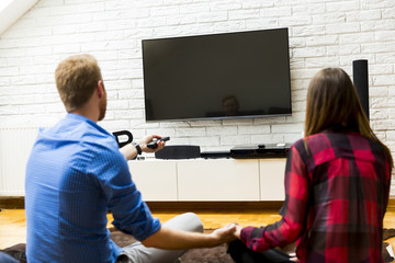 Couple watching television sitting comfortably on floor