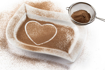 strainer with cocoa while heart shape on a white container.