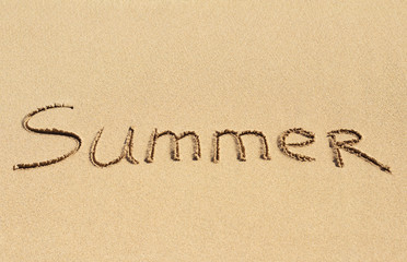 Word Summer handwritten on sand of tropical beach