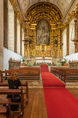 Fototapeta na wymiar Santo Tirso, Portugal. December 26, 2015: Woman praying in the S. Bento monastery. Benedictine order. Built in the Gothic (cloister) and Baroque (church) style.