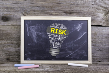 RISK bulb word cloud. Chalk board on a wooden table