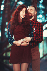 The red-haired guy with a beard and curly red-haired girl on the background of fabulous scenery of nature. Beautiful loving couple on a walk in the woods.