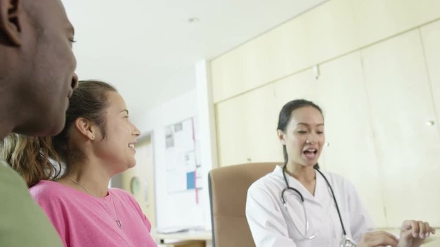  Friendly doctor talking to couple who are expecting a baby in office