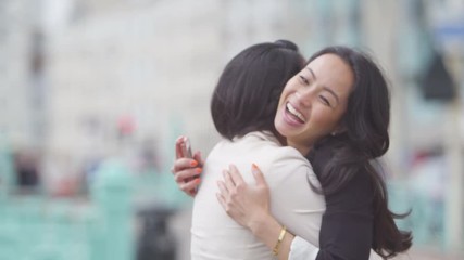  Attractive female friends meet up and greet each other outdoors in the city