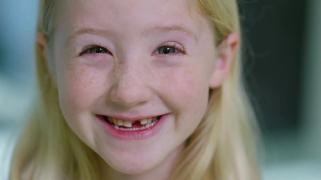  Close up portrait of little girl opening her mouth to show where she has lost one of her baby teeth. 