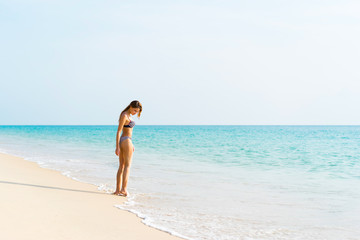 Young beautiful woman in swimwear standing alone on the beach.